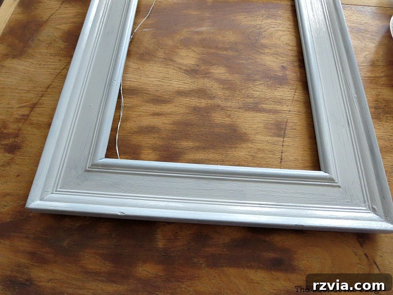The picture frame after being painted a soft metallic gray, a perfect base for the DIY jewelry organizer. The paint adds a subtle shimmer and elegant touch.
