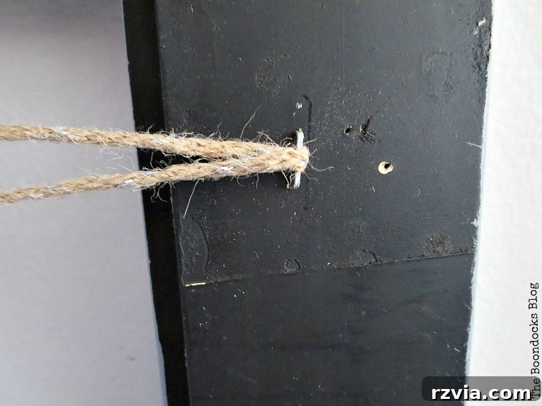 Twine passed through a staple on the back of the frame, illustrating the start of the zigzagging pattern for the DIY jewelry organizer.