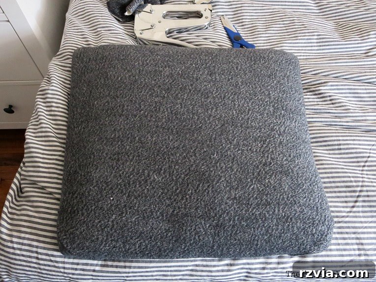 Repurposing an old sweatshirt as upholstery fabric for the chair seat, an eco-friendly and budget-conscious DIY choice.