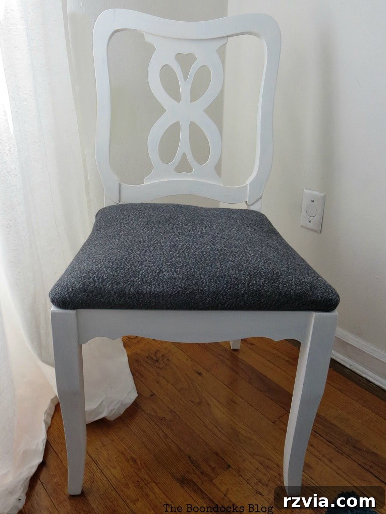 The first finished chair, featuring a crisp white frame and simple upholstery, perfectly complementing a modern black and white bedroom theme.