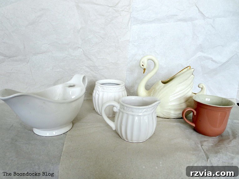 Beyond the Bin: DIY Upcycled Planters 4 A selection of household items including ceramic cups, a gravy boat, a sugar and creamer set, and a ceramic swan, all primed for repurposing into unique planters.
