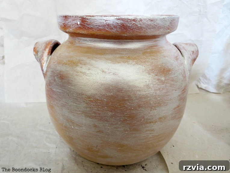 Beyond the Bin: DIY Upcycled Planters 6 An elegant clay pot, painted with decorative white wax, ready to be repurposed as a charming and stylish plant container.