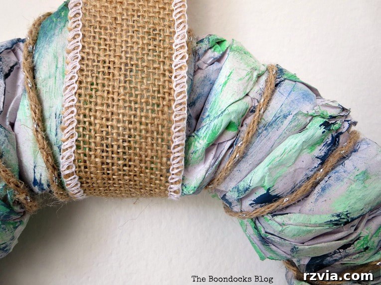 Bright Ideas Easy Colorful Packing Paper Wreath 11 Burlap ribbon being added to the top of the DIY paper wreath to create a functional and stylish hanger, completing the crafting process.