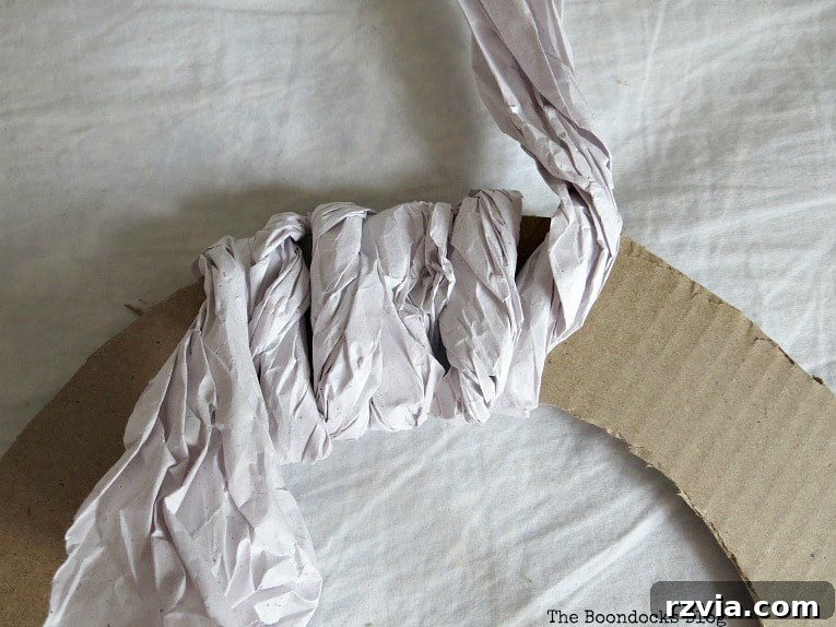 Bright Ideas Easy Colorful Packing Paper Wreath 6 Hands carefully wrapping twisted packing paper around the cardboard wreath base, showing the technique for creating a full and textured DIY wreath.