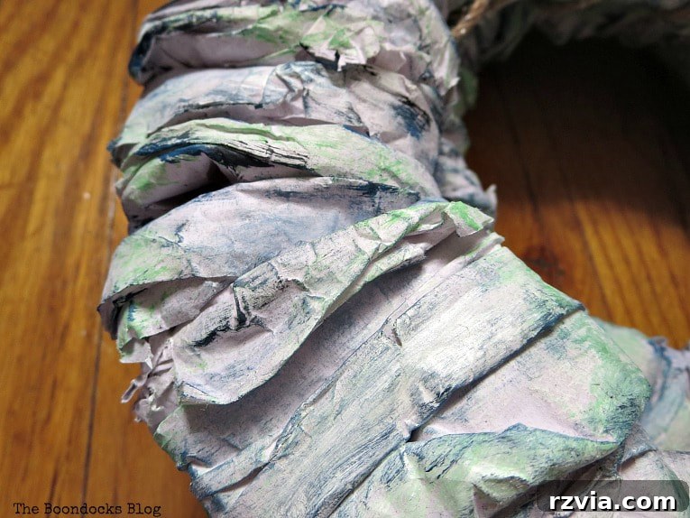 Bright Ideas Easy Colorful Packing Paper Wreath 9 A DIY paper wreath adorned with layers of green, blue, and white paint, demonstrating the multi-tonal painting technique for a rich, textured finish.
