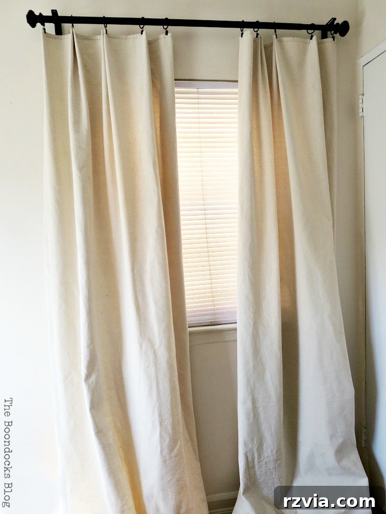 Crafting Elegant Pleated Curtains from Humble Drop Cloths 13 A room featuring newly installed, elegant pleated drop cloth curtains that perfectly match the wall color, enhancing the decor.