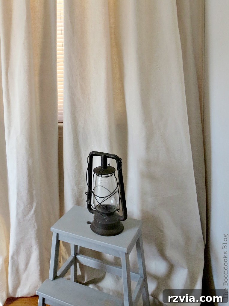 Crafting Elegant Pleated Curtains from Humble Drop Cloths 16 The bottom of a new drop cloth curtain creating a 'puddle' effect on the floor, showcasing generous length and elegant drape.