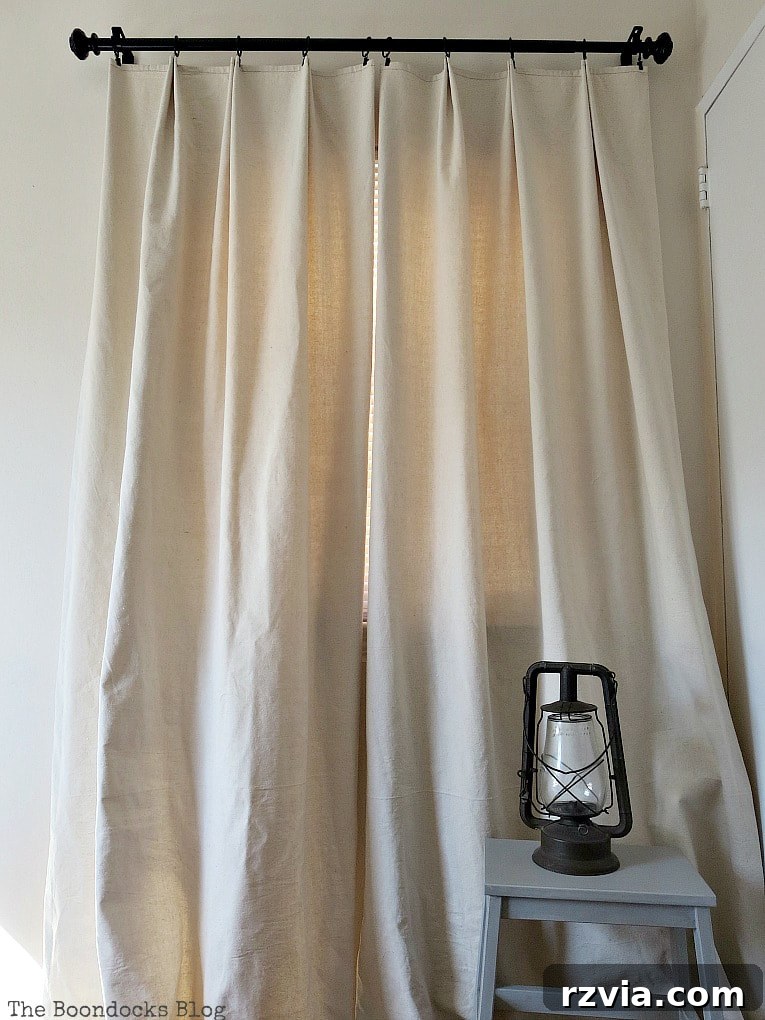 Crafting Elegant Pleated Curtains from Humble Drop Cloths 18 Close-up of a perfectly pleated drop cloth curtain hanging elegantly from a black rod with clip rings.