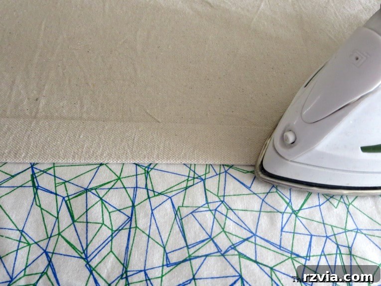 Crafting Elegant Pleated Curtains from Humble Drop Cloths 5 Close-up of a drop cloth panel with an edge neatly folded and pressed with an iron, ready for hemming.