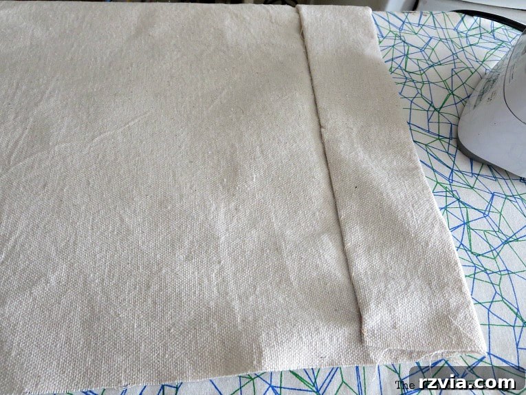 Crafting Elegant Pleated Curtains from Humble Drop Cloths 7 Close-up of a neatly hemmed bottom edge of a drop cloth curtain panel, showcasing the finished seam.