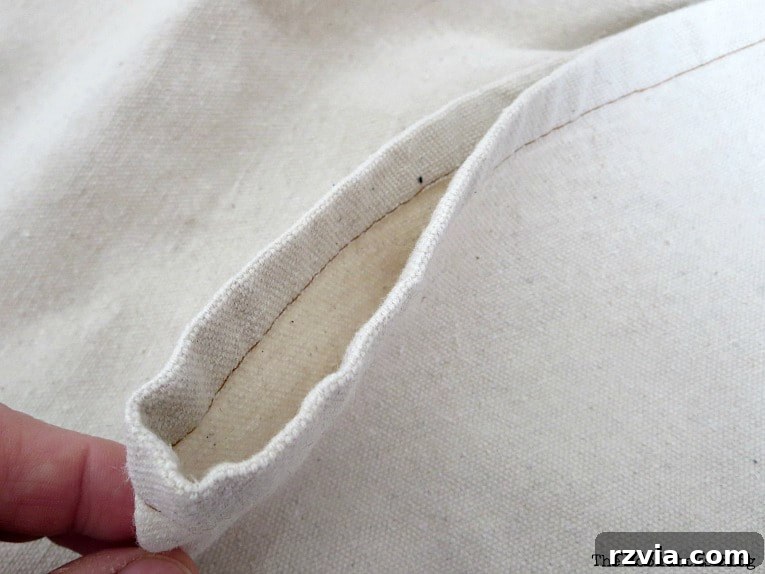 Crafting Elegant Pleated Curtains from Humble Drop Cloths 8 A hand demonstrating how to fold a drop cloth curtain panel to create a pleat for clip rings.