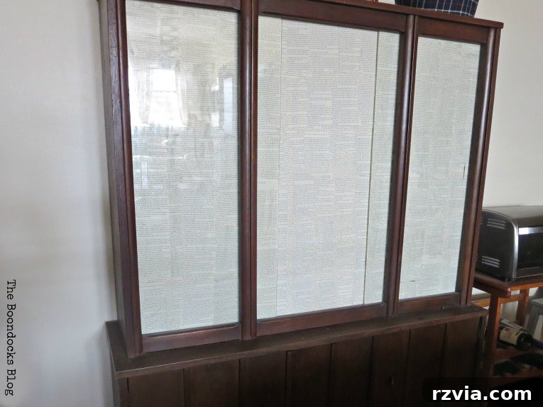 Revitalize Your MCM China Cabinet 15 Close-up of the upper cabinet's glass doors after being decoupaged with book pages, offering a discreet and stylish storage solution.
