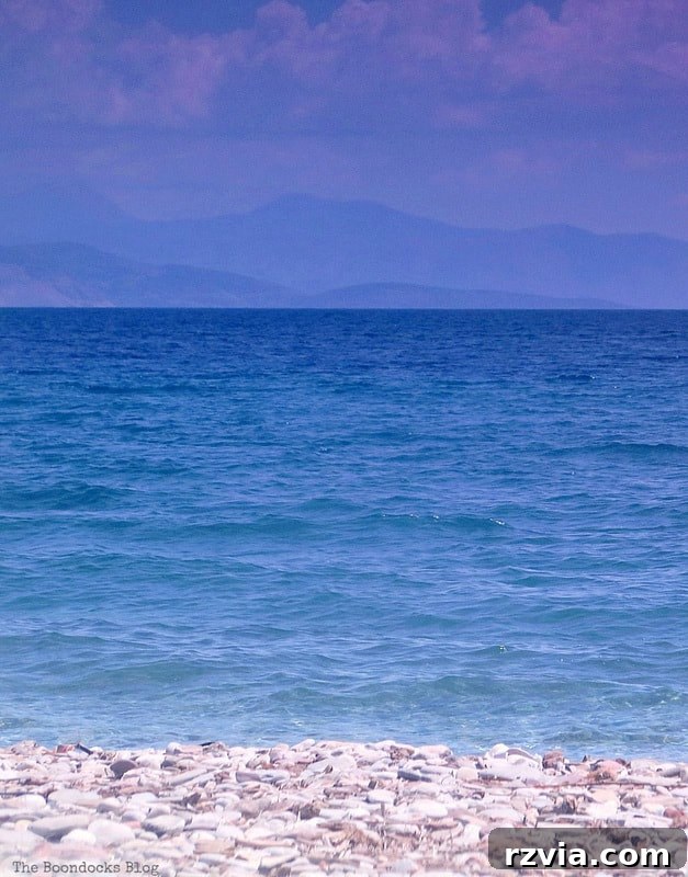 Impressionism Made Simple: A Painting Tutorial 7 Inspiration image: Photograph of a tranquil pebble beach and sea with sky and distant mountains