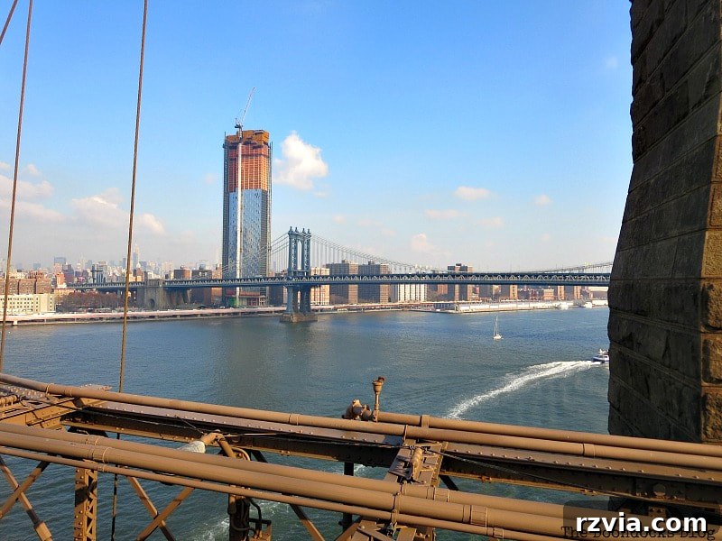 A panoramic view of the East River and the Manhattan Bridge from the Brooklyn Bridge, capturing the dynamic cityscape. A Tour of the Astonishing Brooklyn Bridge Walkway.