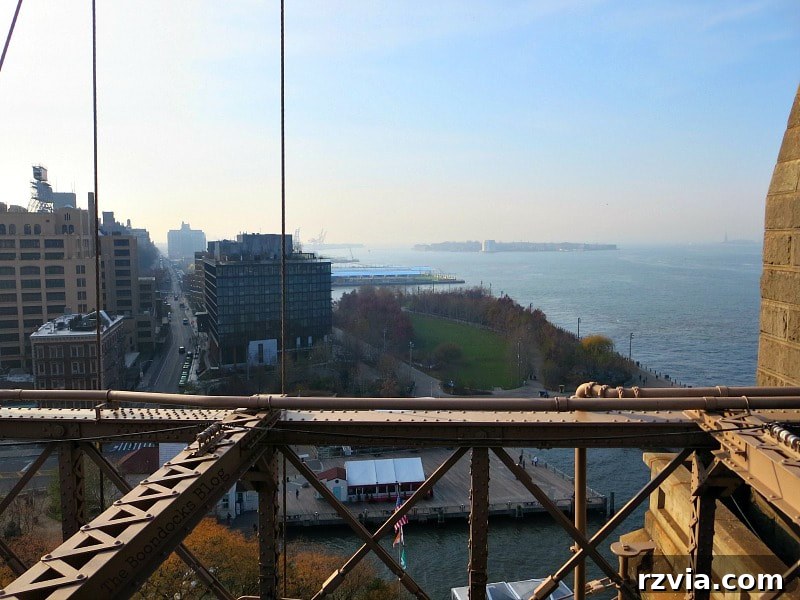 Looking south from the Brooklyn Bridge to the vibrant Brooklyn Bridge Park, with Governors Island in the background. A Tour of the Astonishing Brooklyn Bridge Walkway.