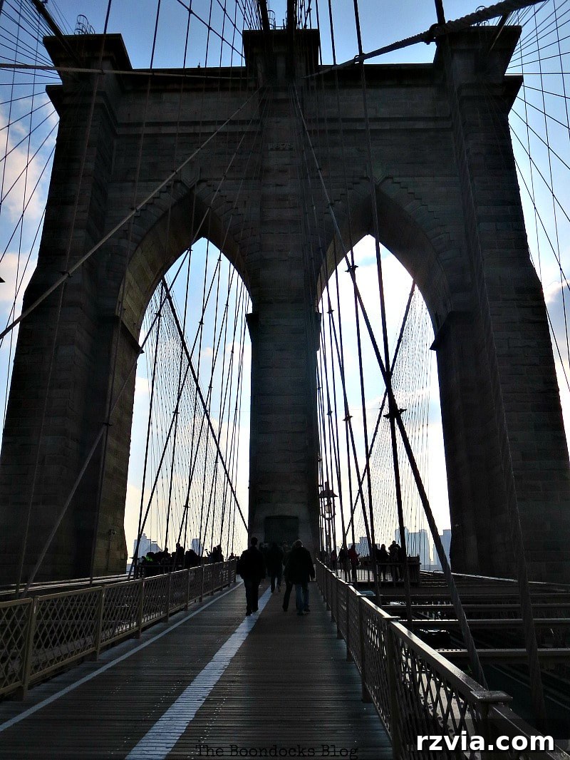 Approaching the massive first tower of the Brooklyn Bridge, highlighting the intricate details and pedestrian walkway. A Tour of the Astonishing Brooklyn Bridge Walkway.