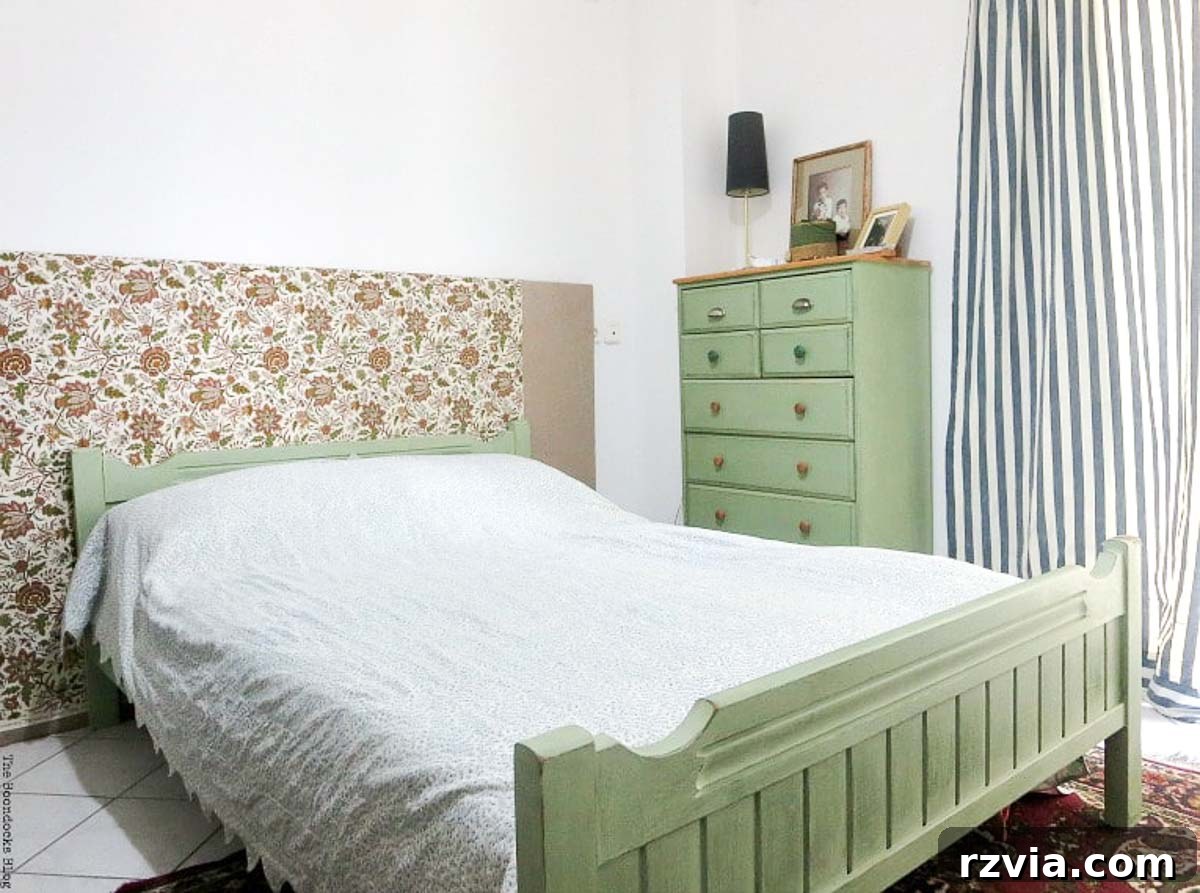 A beautifully painted olive green dresser and matching bed frame anchor the bedroom. The bed features a charming floral fabric headboard, adding a touch of softness and elegance.