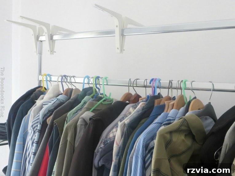 A minimalist clothing rack neatly displaying various clothes on hangers, highlighting the need for a covering solution to maintain tidiness.
