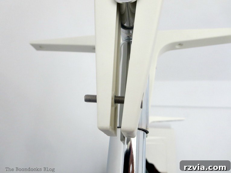 A close-up shot of an IKEA EKBY shelf bracket securely screwed into the top bar of a clothing rod, forming a stable base for the cover structure.