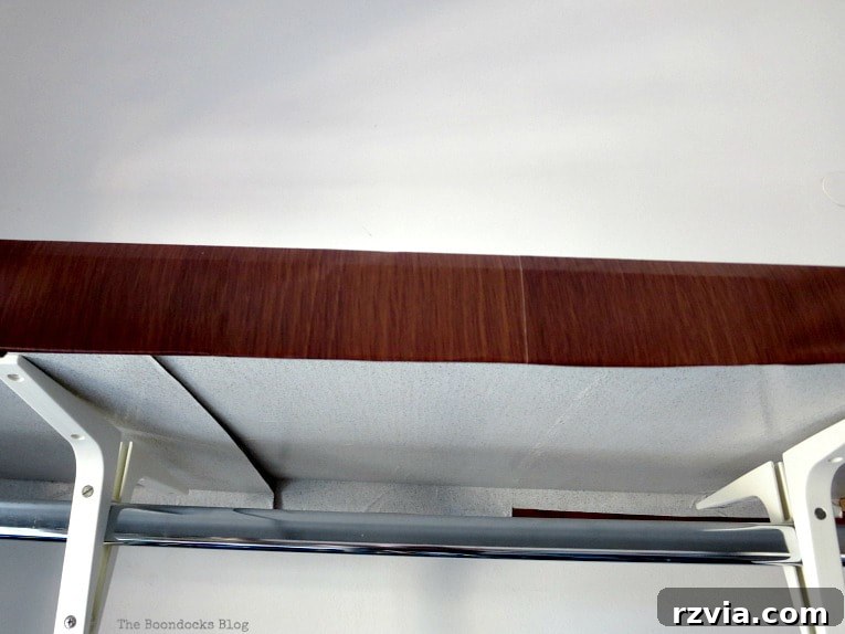 A meticulously covered cardboard frame, featuring wood-patterned contact paper on the outside and a lighter, patterned contact paper on the inside, ready for fabric attachment.