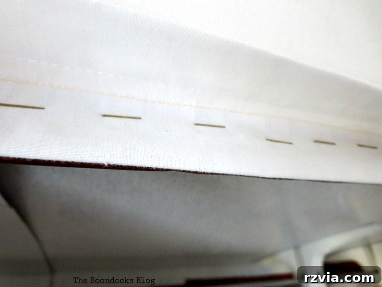 The completed attachment of white sheets to the cardboard frame, showing the fabric securely stapled and ready to enclose the clothing rack.