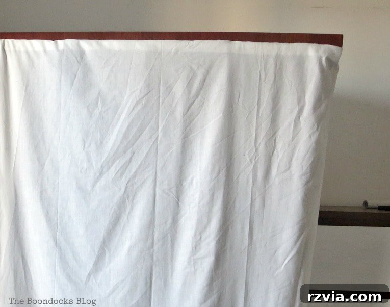 A close-up view of the white sheet fabric used for the clothes rack cover, showing its texture and how it drapes around the hidden structure.