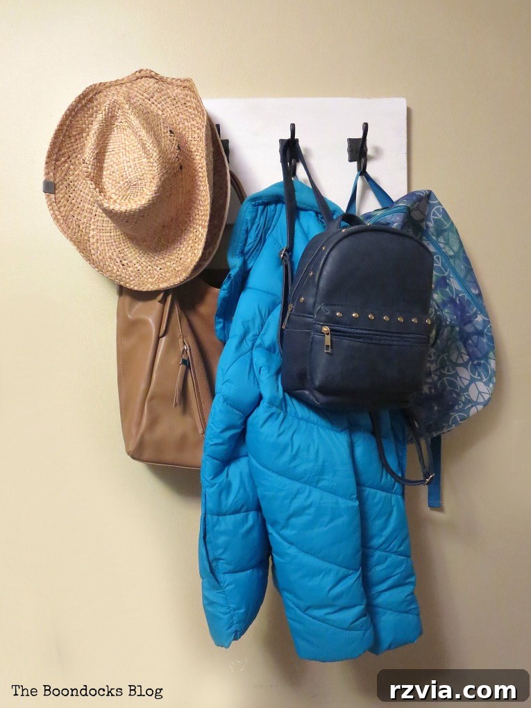 A 'reality shot' of a DIY wooden wall hanger, laden with various items on its dark gunmetal hooks, highlighting its practical use for everyday home organization.