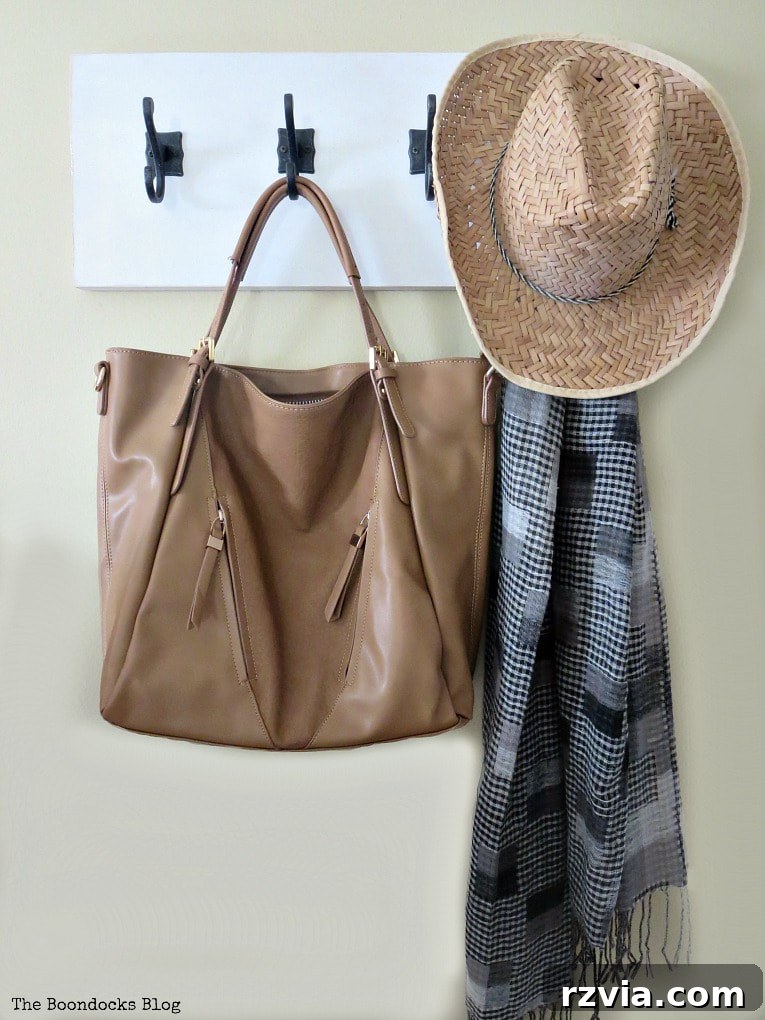 A simple yet elegant DIY wooden wall hanger, featuring a white painted board and dark gunmetal hooks, ready to enhance home organization with a clean farmhouse look.