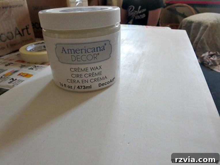 Applying clear cream wax to a painted wooden board, a crucial step in finishing a DIY wall hanger. This protects the chalk paint and provides a smooth, durable surface.