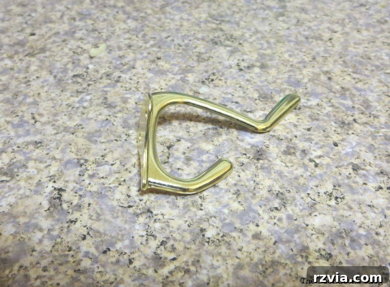 A close-up of a 'wrong' hook, illustrating the disappointment of finding fake gold hardware that doesn't fit the desired aesthetic for a DIY wall hanger.
