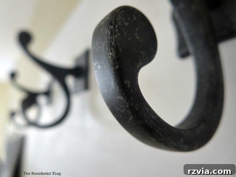 Close-up of the elegant curve of a dark gunmetal metal hook, emphasizing its quality and design on a DIY wooden wall hanger.