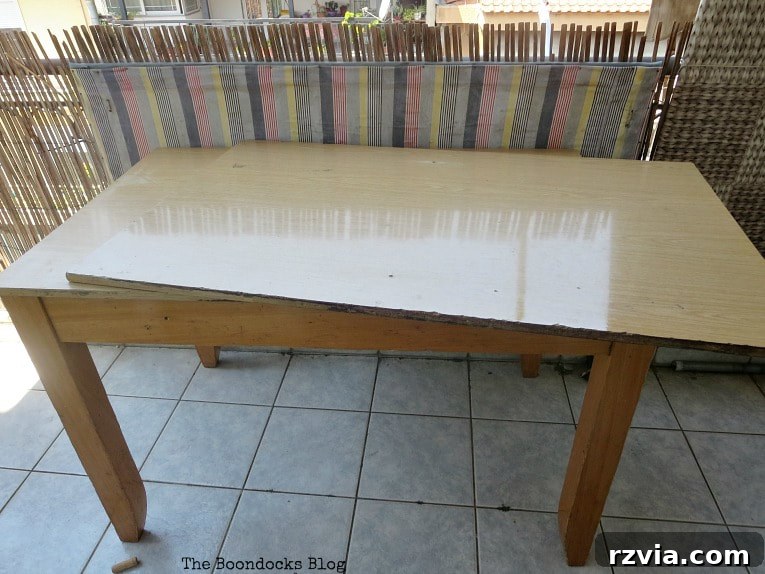 Before image of the worn laminate table, showcasing its original condition.