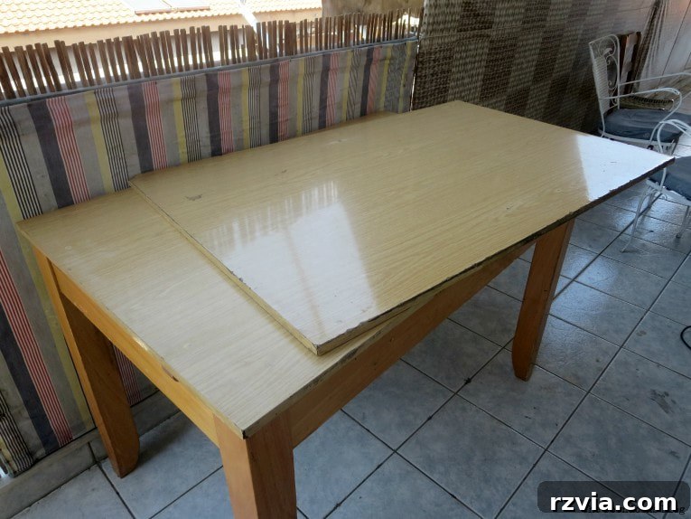 Before shot of a worn laminate table with visible damage and wear.