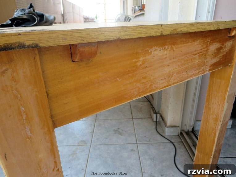 Close-up of the laminate table's leaves and damaged areas before restoration.