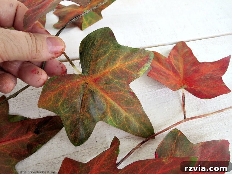 Dollar Store Vine Transformed into a Gorgeous Fall Wreath 4 Painting the plastic leaves of the dollar store vine with fall colors like red and yellow for a beautiful DIY fall wreath.