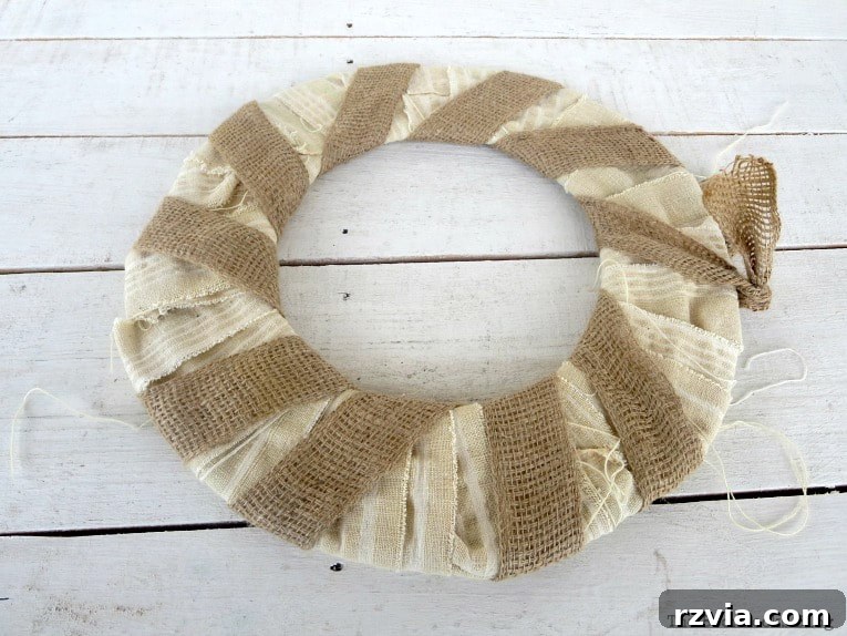 Dollar Store Vine Transformed into a Gorgeous Fall Wreath 8 Wreath base wrapped with white fabric strips and then layered with burlap ribbon, creating a textured foundation for the DIY fall wreath.