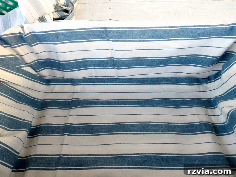 Fabric Fix: Giving New Life to Old Plastic Baskets 7 The blue and white striped fabric now folded over both long sides of the green plastic basket, showing a neatly wrapped edge.