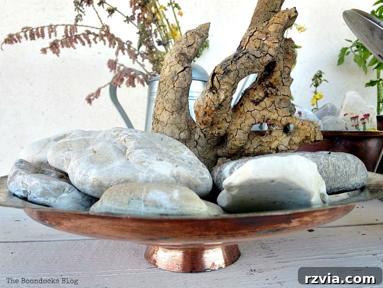 Copper Pot Upcycling Nightmares 9 Copper lid adorned with rocks and a mysterious wood stump, part of the failed vignette