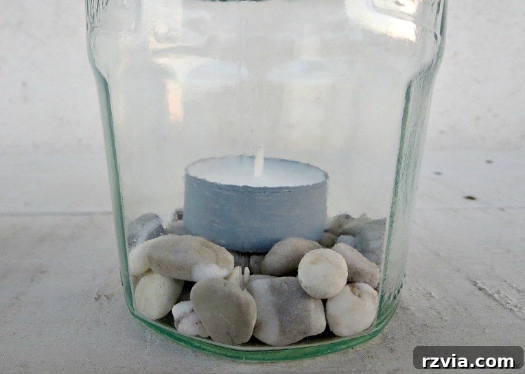 Transform Jars into Glowing Lanterns 14 Close-up of pebbles and a tea light candle placed inside a newly crafted mason jar lantern, ready to illuminate any space.