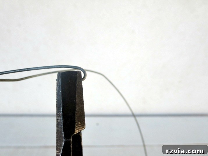 Transform Jars into Glowing Lanterns 5 Close-up of a hand using pliers to make a small loop or hook at the end of a craft wire, an essential first step for simple DIY lanterns.