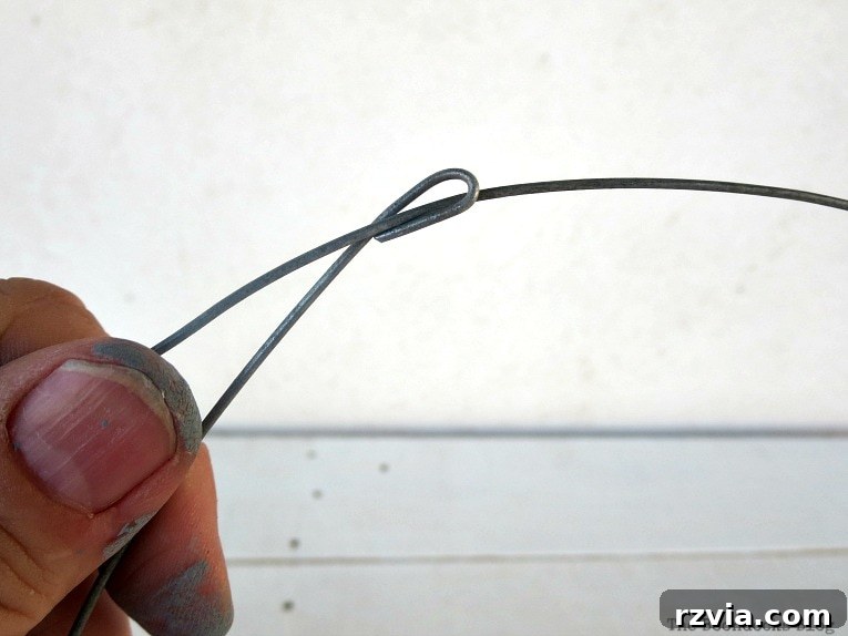 Transform Jars into Glowing Lanterns 7 Passing the free end of the craft wire through the initial hook to form a secure circle, an important step in making simple DIY lanterns with repurposed jars.