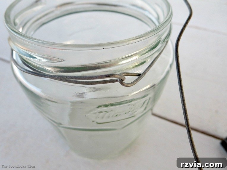 Transform Jars into Glowing Lanterns 9 The process of pulling the wire in the opposite direction to form a second, reinforcing circle around the jar's rim for a secure DIY lantern frame.