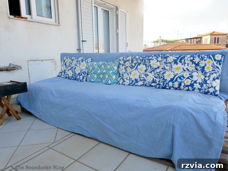 Super Simple Pallet Couch No Tools Needed 12 The pallet couch draped with fabric and adorned with cushions, instantly transforming its appearance.