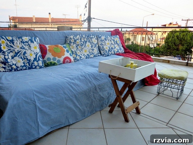 Super Simple Pallet Couch No Tools Needed 13 The completed DIY pallet couch, adorned with colorful cushions and a red throw blanket, ready for relaxation.