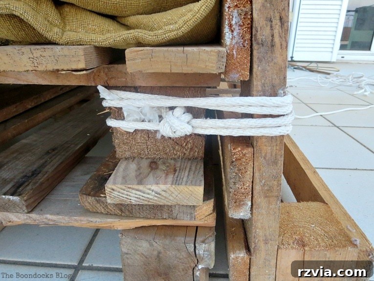 Super Simple Pallet Couch No Tools Needed 7 Securing the backrest pallet to the top seat pallet using rope, demonstrating the no-tool fastening method.