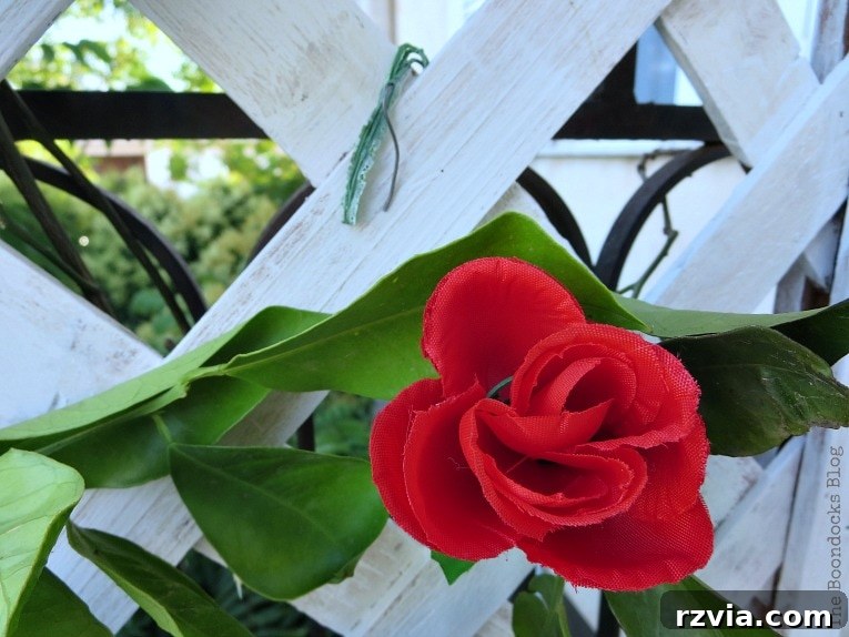 Budget Blooms: Brighten Your Fence 11 A faux flower stem bent into a hook shape, ready to be hung on the lattice flower wall, showing ingenious placement.