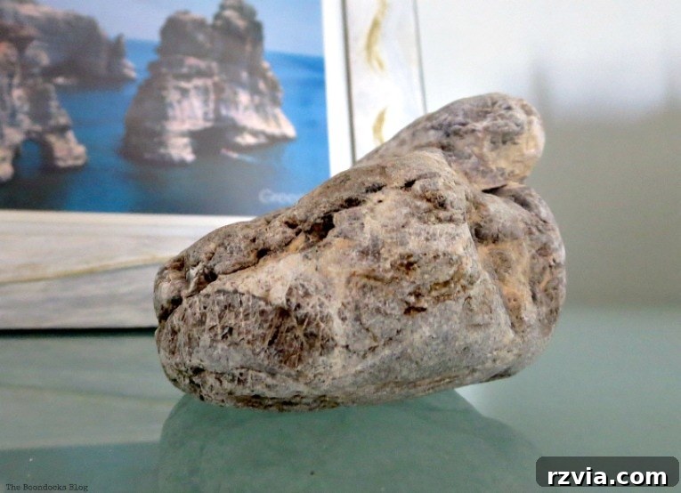 Upcycled Bookcases: Crafting Success, Avoiding Pitfalls 12 A smooth beach stone carefully placed in front of a framed postcard depicting a unique rock formation.