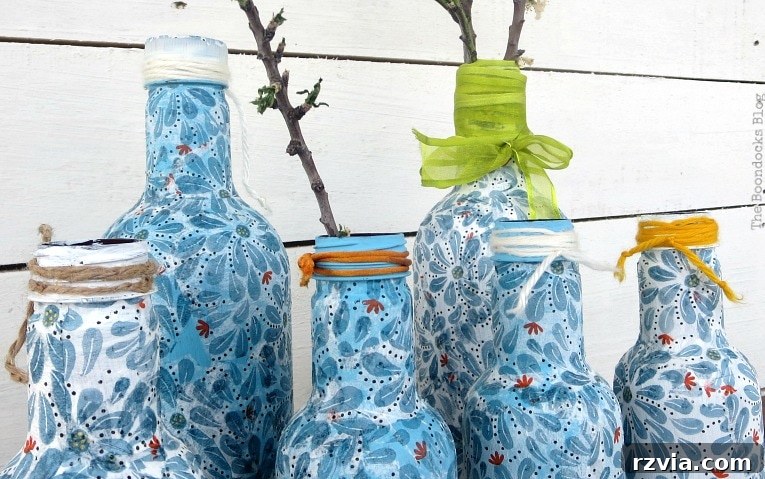 Ribbons, yarn and cords added as embellishment to finished decoupaged bottles, providing decorative details.