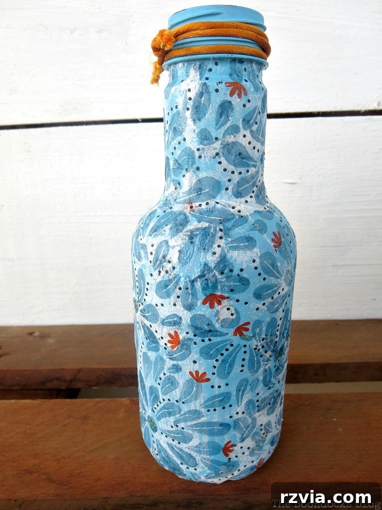Blue decoupaged bottle, showing areas where the white napkin overlaps slightly, a common minor imperfection.