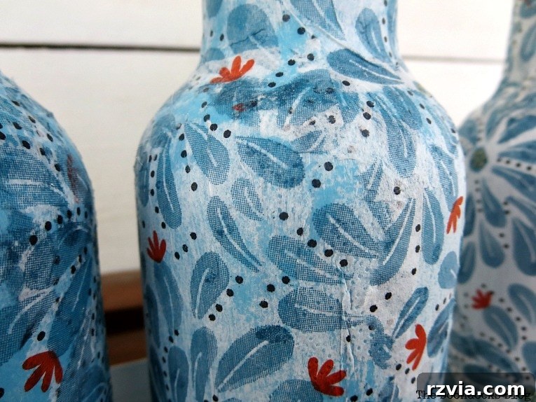 Bottle decoupaged with blue paint showing through, illustrating a learning moment.